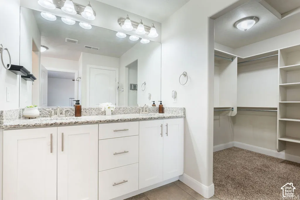 Dual vanity with a stone countertop, individual sinks, and a large wall-mounted mirror