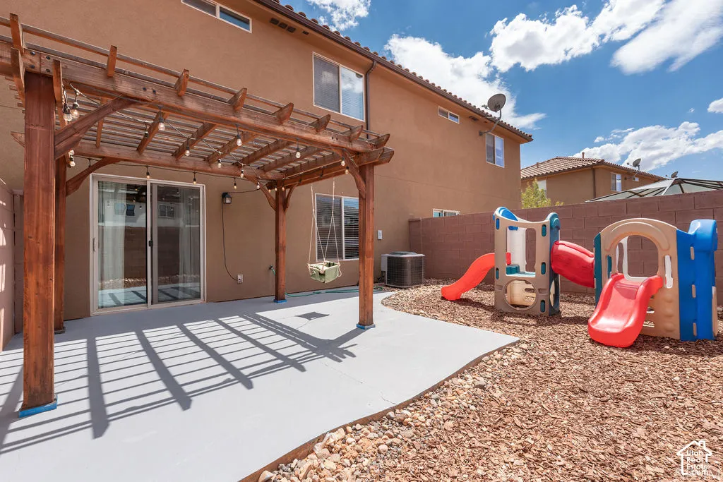 Private backyard featuring a wooden pergola, concrete patio, and bark chip landscaping