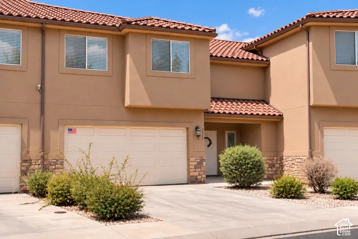 Stucco exterior with a tile roof, multi-pane windows, and an attached garage