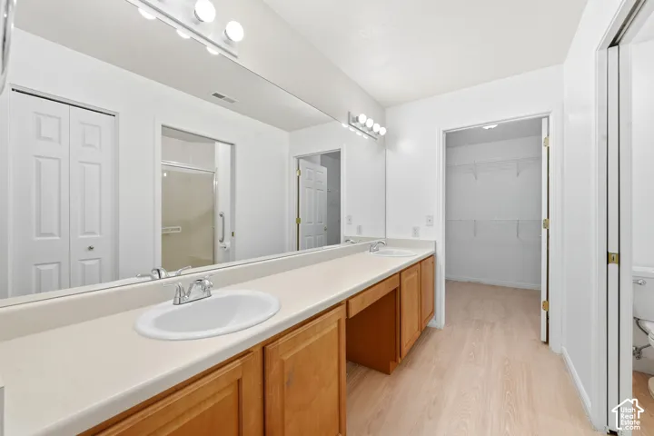Dual vanity with integrated sinks, wood-finish cabinetry, full-width mirror, and lighting