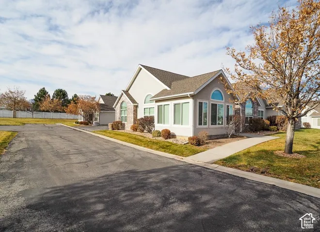 Stucco exterior with brick accents, arched window details, multiple large windows, and a paved driveway