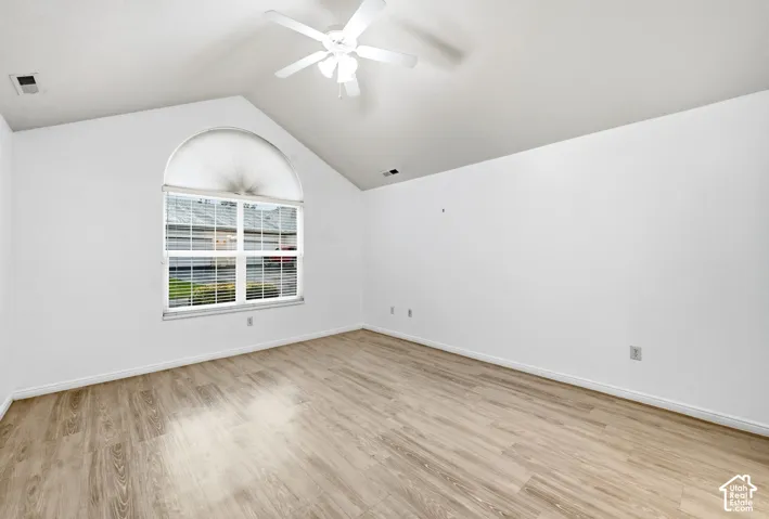 Primary Bedroom Ensuite - Vaulted ceiling with a ceiling fan, arched window with blinds, and wood-finish flooring