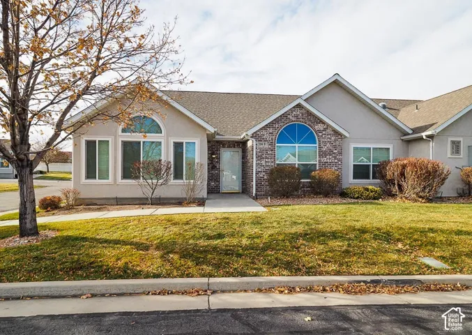 Stucco exterior with brick accents, arched window features, asphalt shingle roofing, and established landscaping