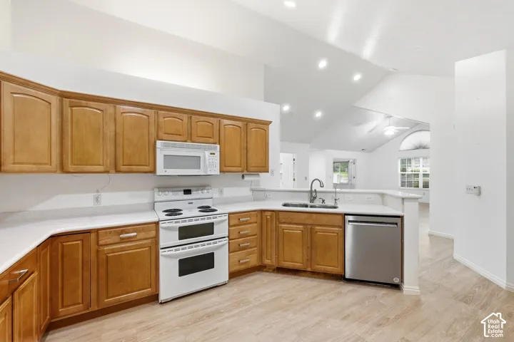 Kitchen featuring wood-finish cabinetry, white countertops, a double oven range, stainless steel dishwasher, and wood-finish flooring
