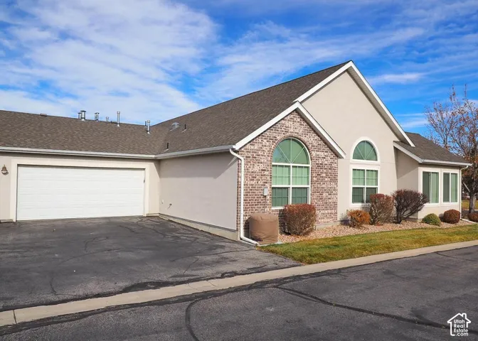Stucco and brick exterior with arched window details and 2-car garage