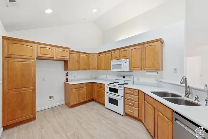 Kitchen featuring wood cabinetry, white countertops, a double basin sink, and wood-finish flooring