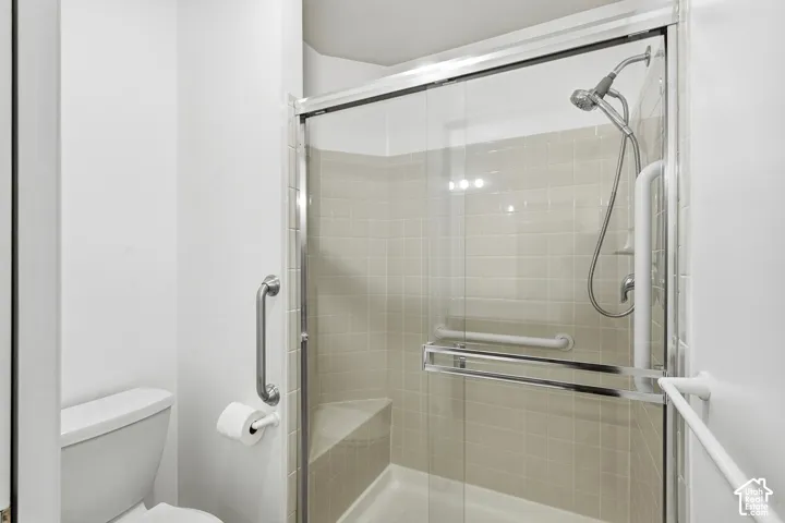 Walk-in shower with clear glass enclosure and neutral-toned wall tiling