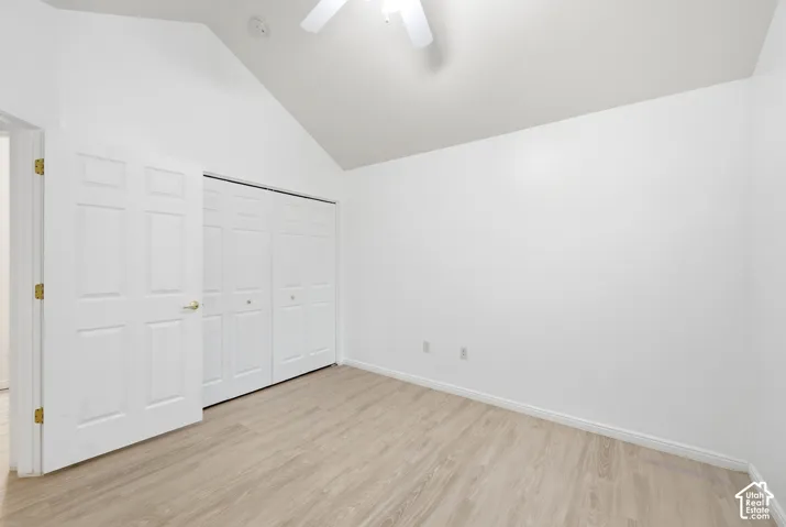 Vaulted ceiling, wood-finish flooring, white walls, bi-fold closet doors, and a ceiling fan