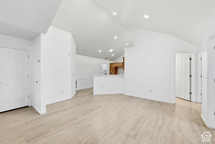 Vaulted ceilings with recessed lighting, wood-finish flooring, white paneled doors, and a partial view of built-in wood cabinetry