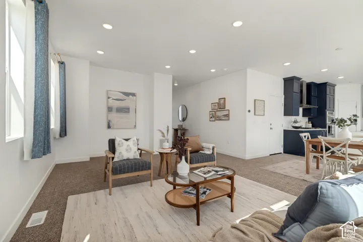 Recessed lighting, white walls, and carpeted flooring in the living area