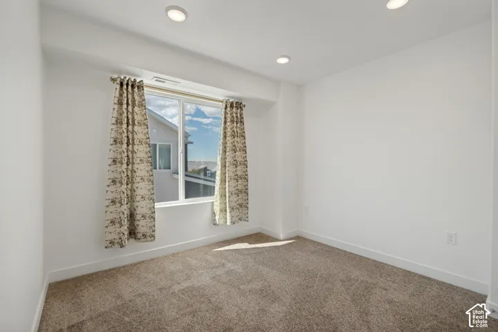 Recessed ceiling lighting, white walls, large window with white frame, and wall-to-wall carpeting