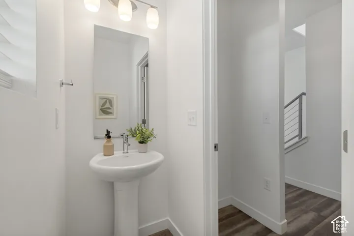 Pedestal sink with chrome faucet, wall-mounted mirror, and three-light vanity fixture