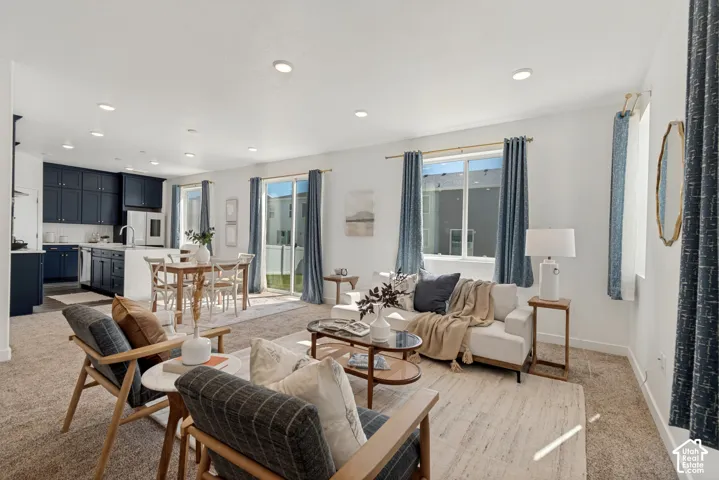 Open-concept living space featuring wood-finish flooring, recessed ceiling lighting, and expansive windows with blue drapery