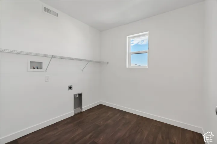 Laundry area featuring wood-finish flooring, white walls, a single window, and a wire shelving unit