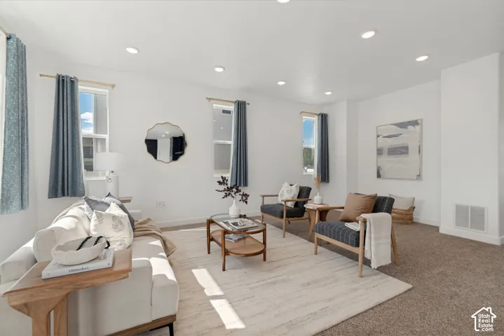 Bright living area featuring recessed lighting, multiple windows, and a combination of carpet and area rug flooring
