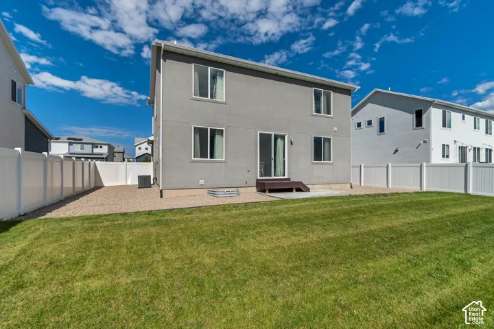 Expansive lawn area with a gravel perimeter, private white fencing, and a concrete patio with wood steps