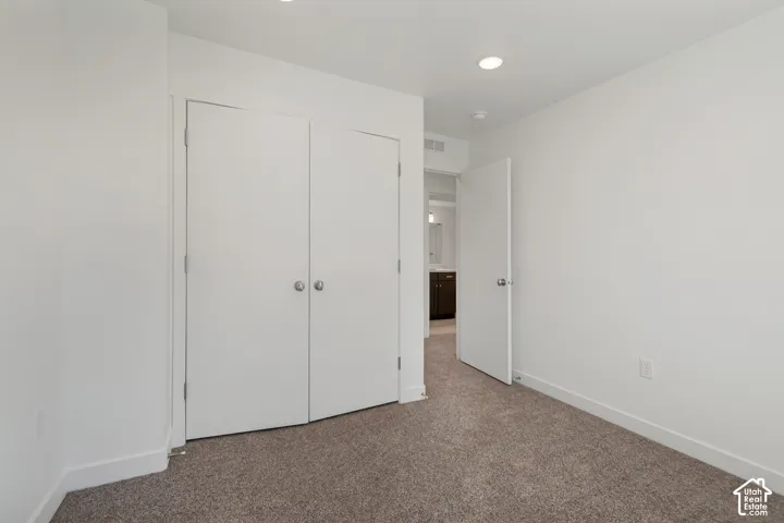 Neutral tone walls with recessed lighting, complemented by textured carpeting and bifold closet doors