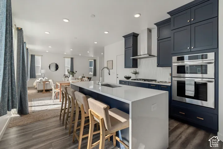 Kitchen featuring a waterfall island, stainless steel appliances, dark cabinetry, and white tile backsplash