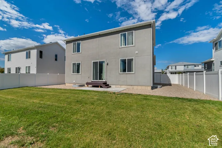 Expansive rear yard featuring green lawn, white privacy fencing, and a gravel perimeter