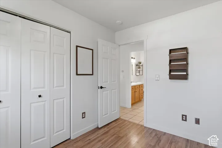 Wood-finish flooring, white paneled bifold closet doors, and a white paneled interior door.