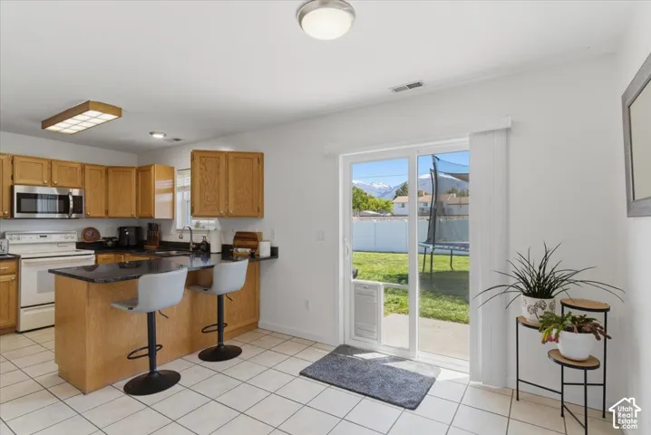 Kitchen featuring wood cabinetry, stainless steel appliances, a center island with bar seating, and tile flooring