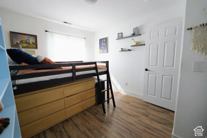 Wood-finish flooring, white paneled door with black hardware, recessed wall shelving, and a prominent window