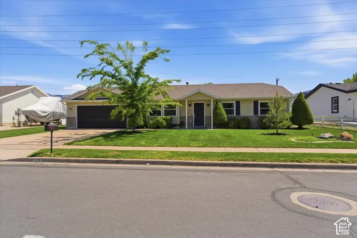 Single-story residence featuring a two-car garage, established front landscaping, and a covered porch entry