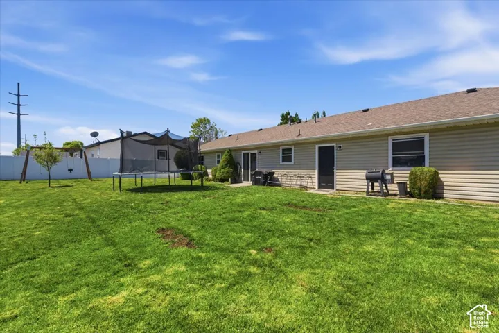 Expansive rear lawn featuring a vinyl privacy fence, two exterior doors, and exterior siding