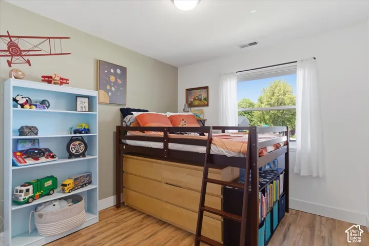 Wood-finish flooring with white baseboards, bright white walls, and a single window with white trim