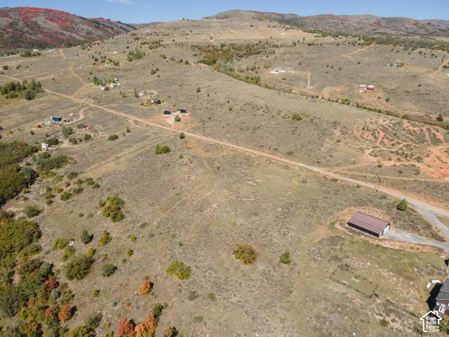 Expansive rural landscape featuring a long dirt road, scattered structures, and distant mountains