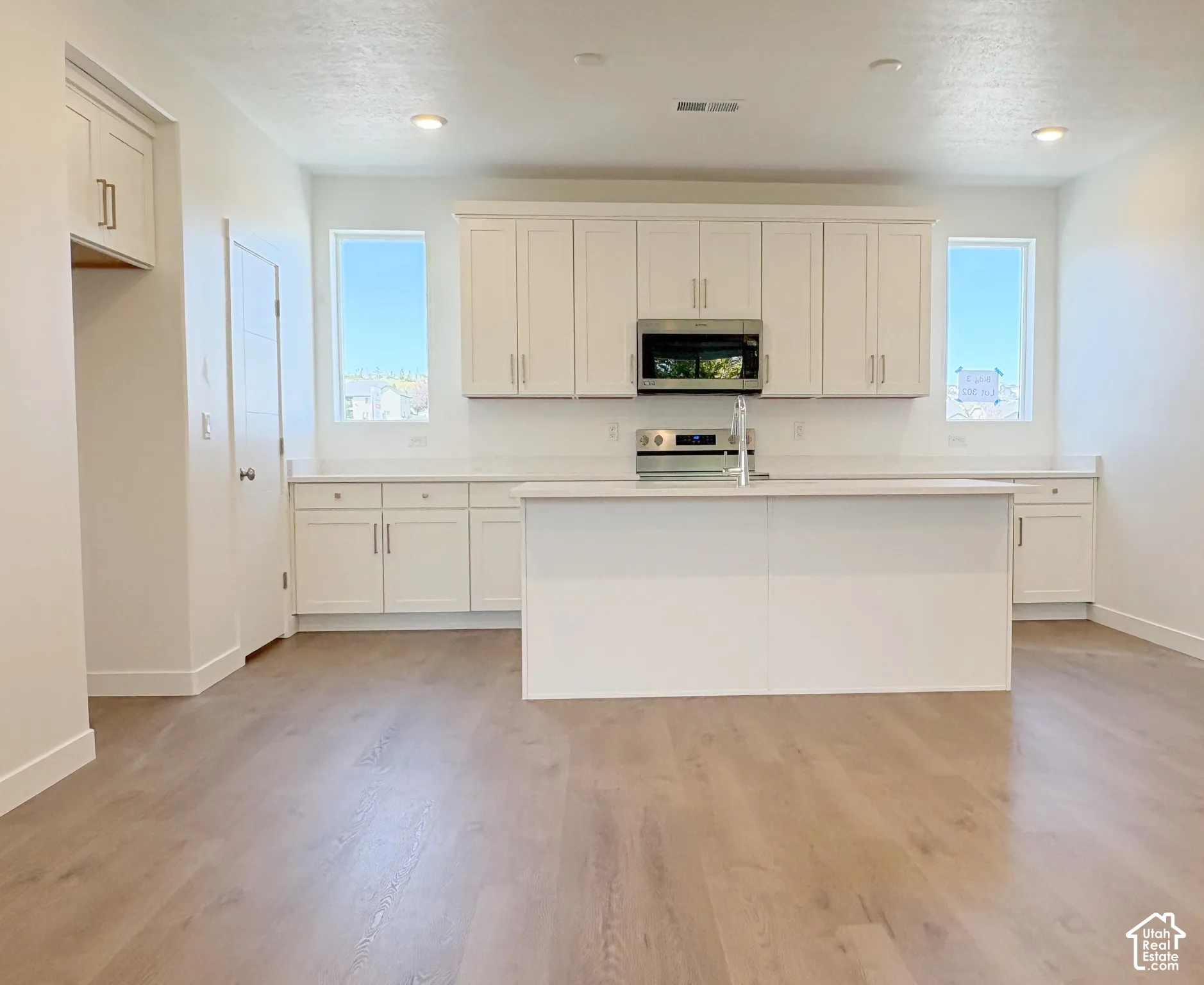Modern kitchen featuring white shaker cabinetry, stainless steel appliances, a center island, and wood-finish flooring