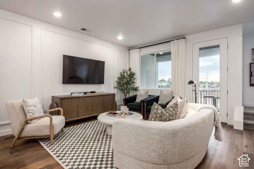 Recessed lighting illuminates wood-finish flooring, a wall-mounted television, and built-in wall paneling