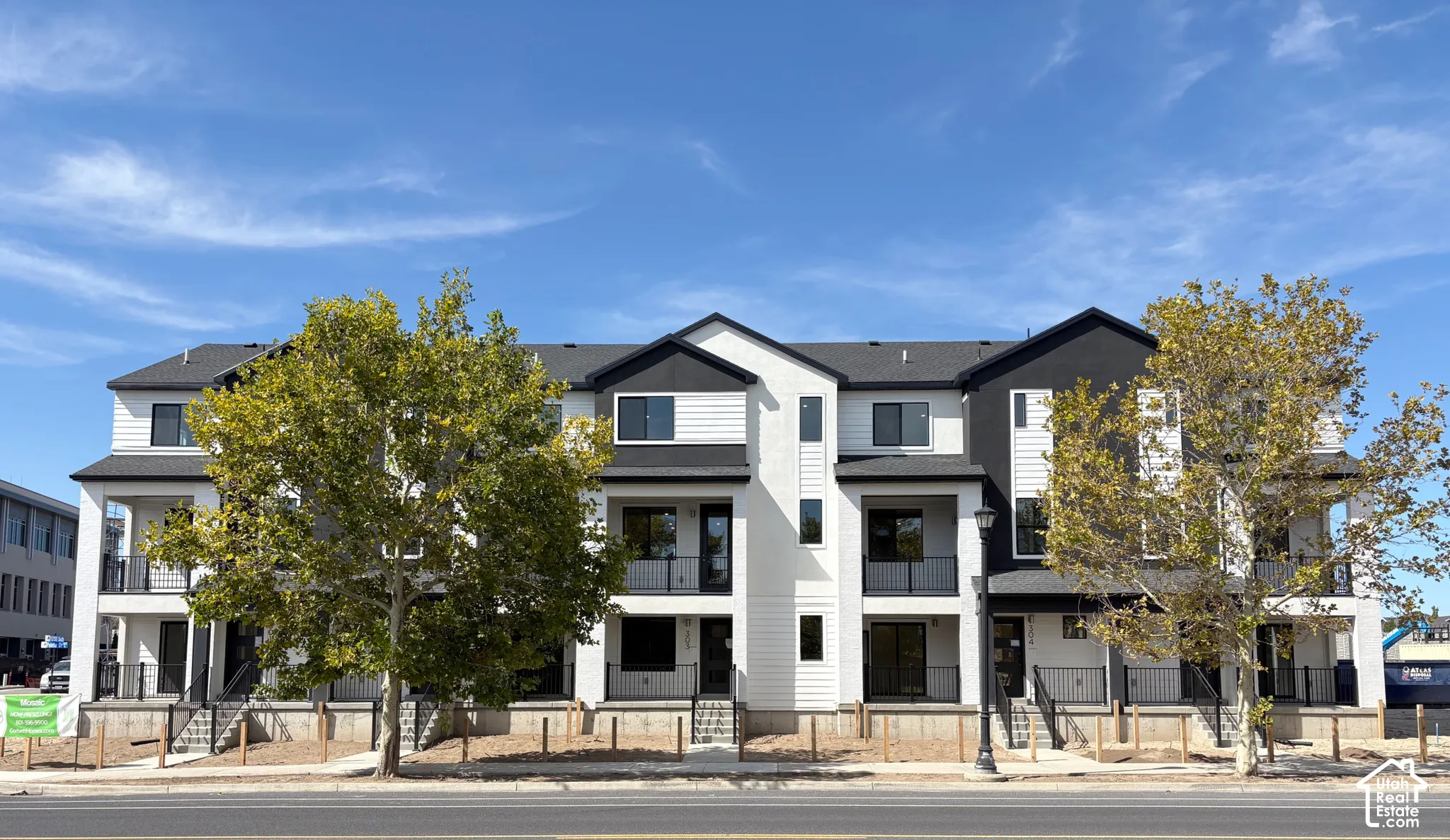 Contemporary townhome-style residences featuring dark-framed windows, private balconies, and a modern black and white exterior