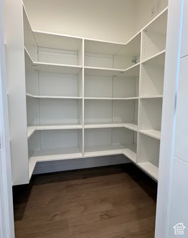 Built-in white shelving system, wood-finish flooring, white walls, and a modern white door
