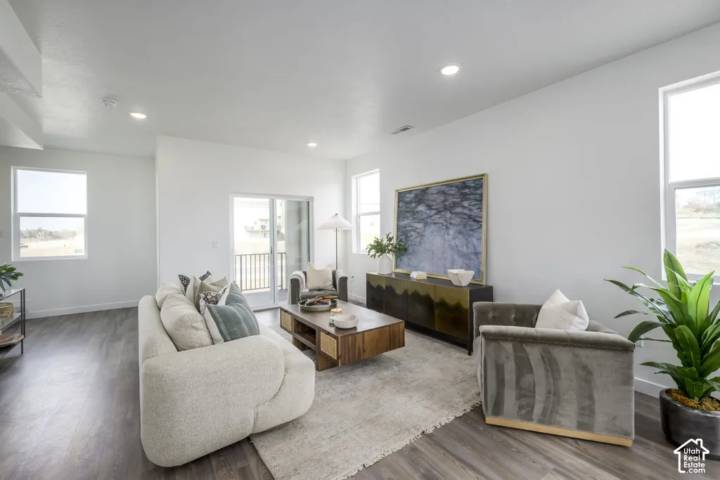 Spacious living area featuring wood-finish flooring, a sliding glass door to an exterior balcony, multiple windows, and recessed lighting