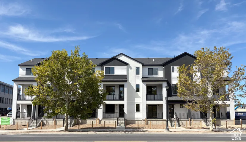 Contemporary townhome-style residences featuring dark-framed windows, private balconies, and a modern black and white exterior