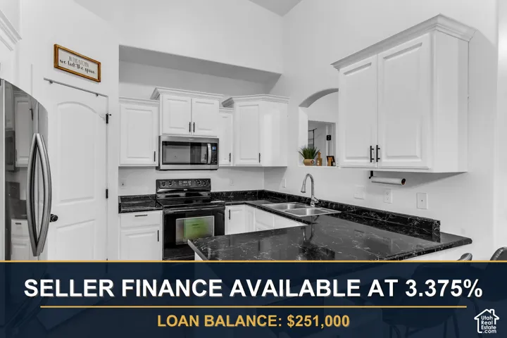 White upper and lower cabinetry, dark stone-finish countertops, stainless steel dual basin sink, and an arched doorway