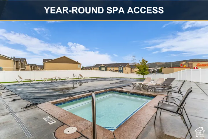 Outdoor spa with tiled interior, concrete surround, and adjacent lounging space