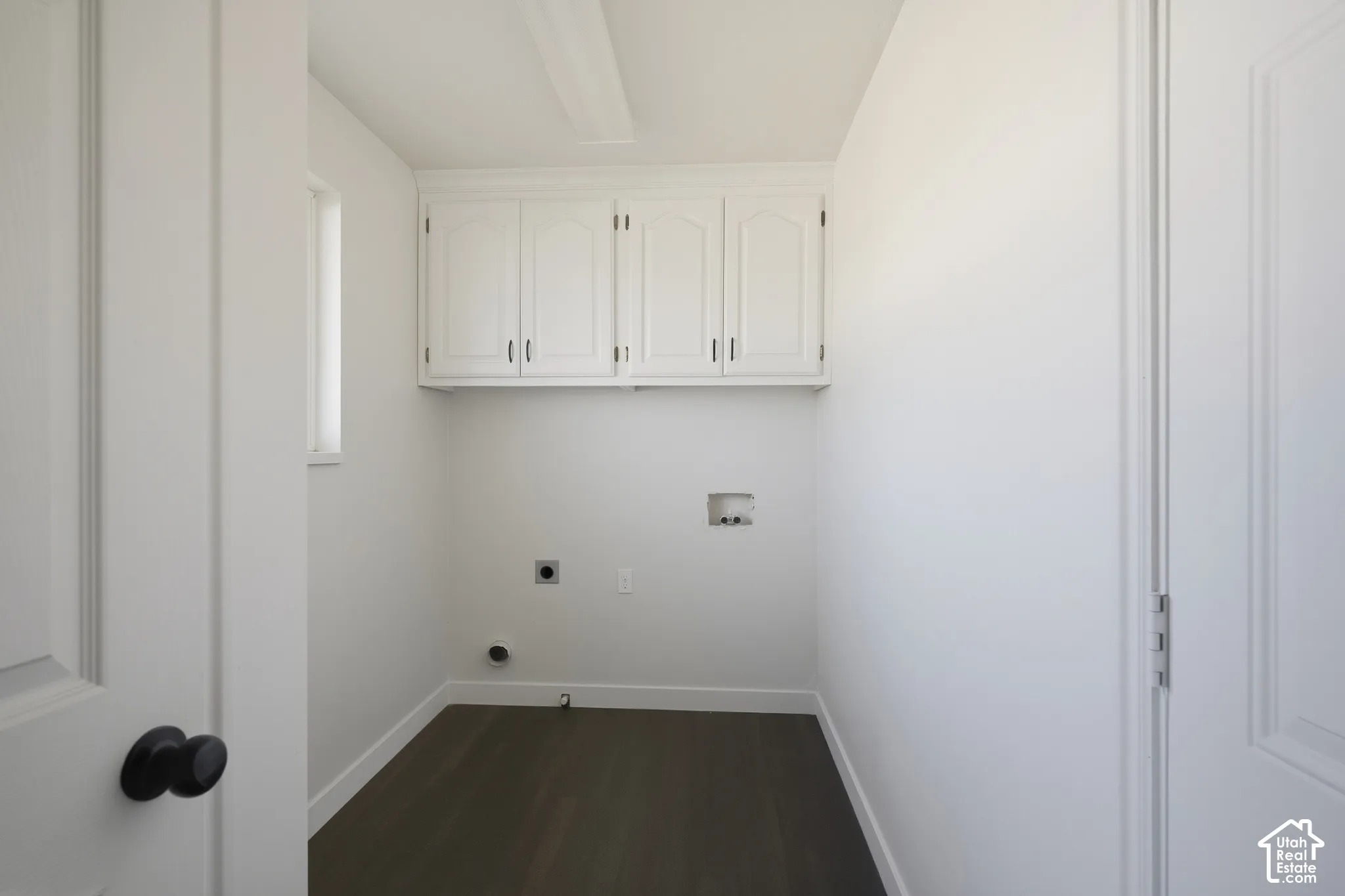 White cabinetry with arched door details, dark wood-finish flooring, and a single window