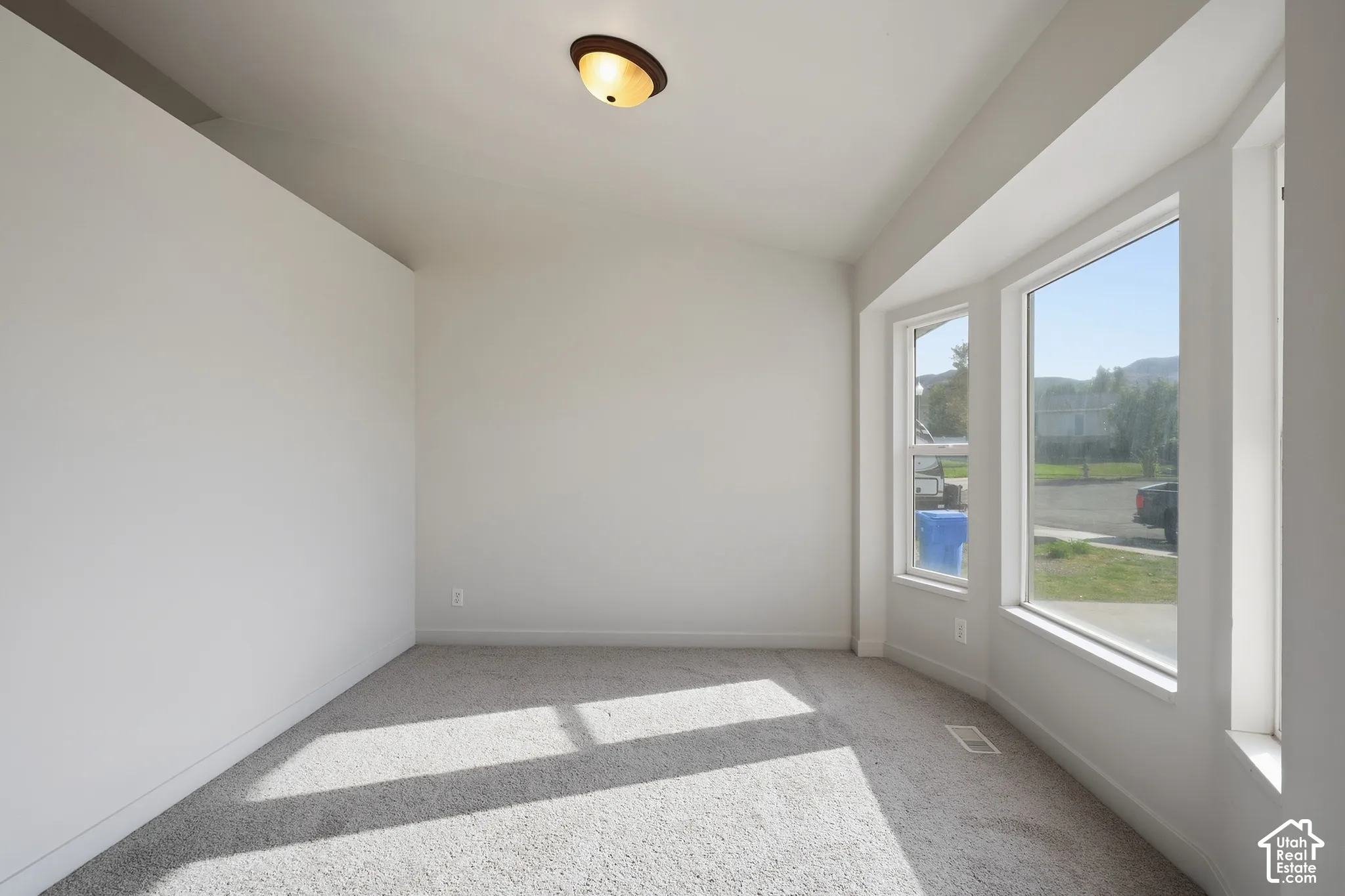 Bay window with white trim, vaulted ceiling, and flush mount light fixture