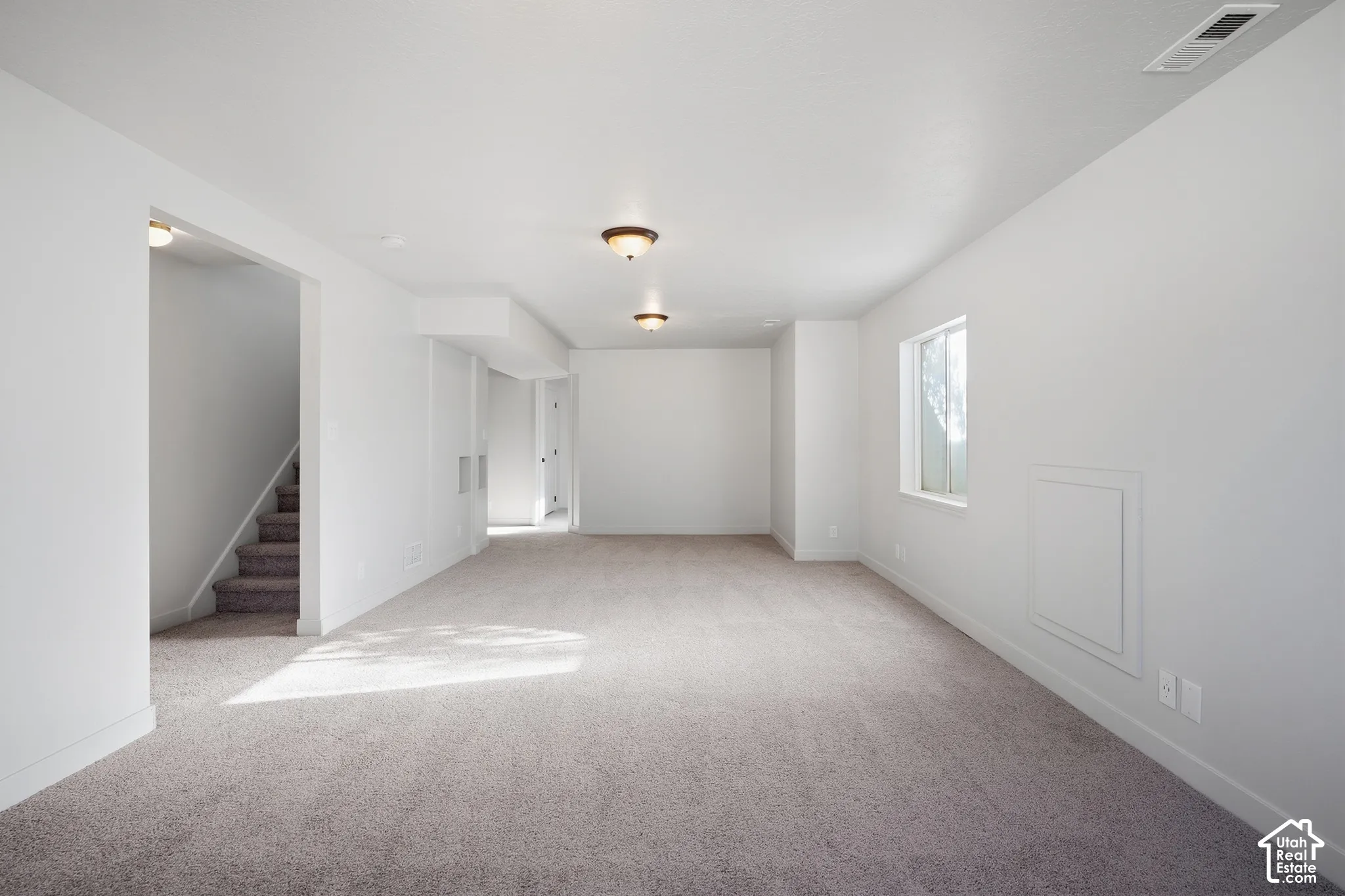 Spacious room featuring neutral carpeting and white walls