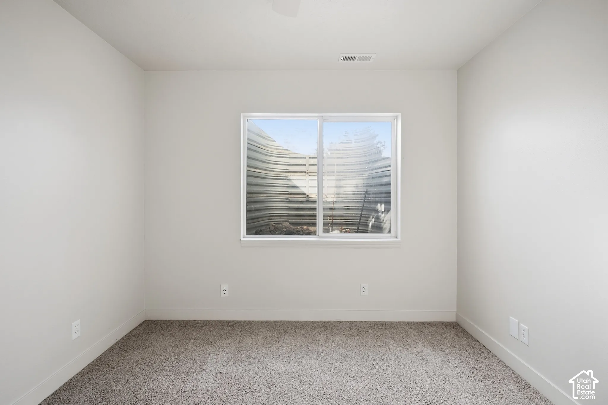 Neutral-toned carpeting, light-colored walls, and a white-framed window