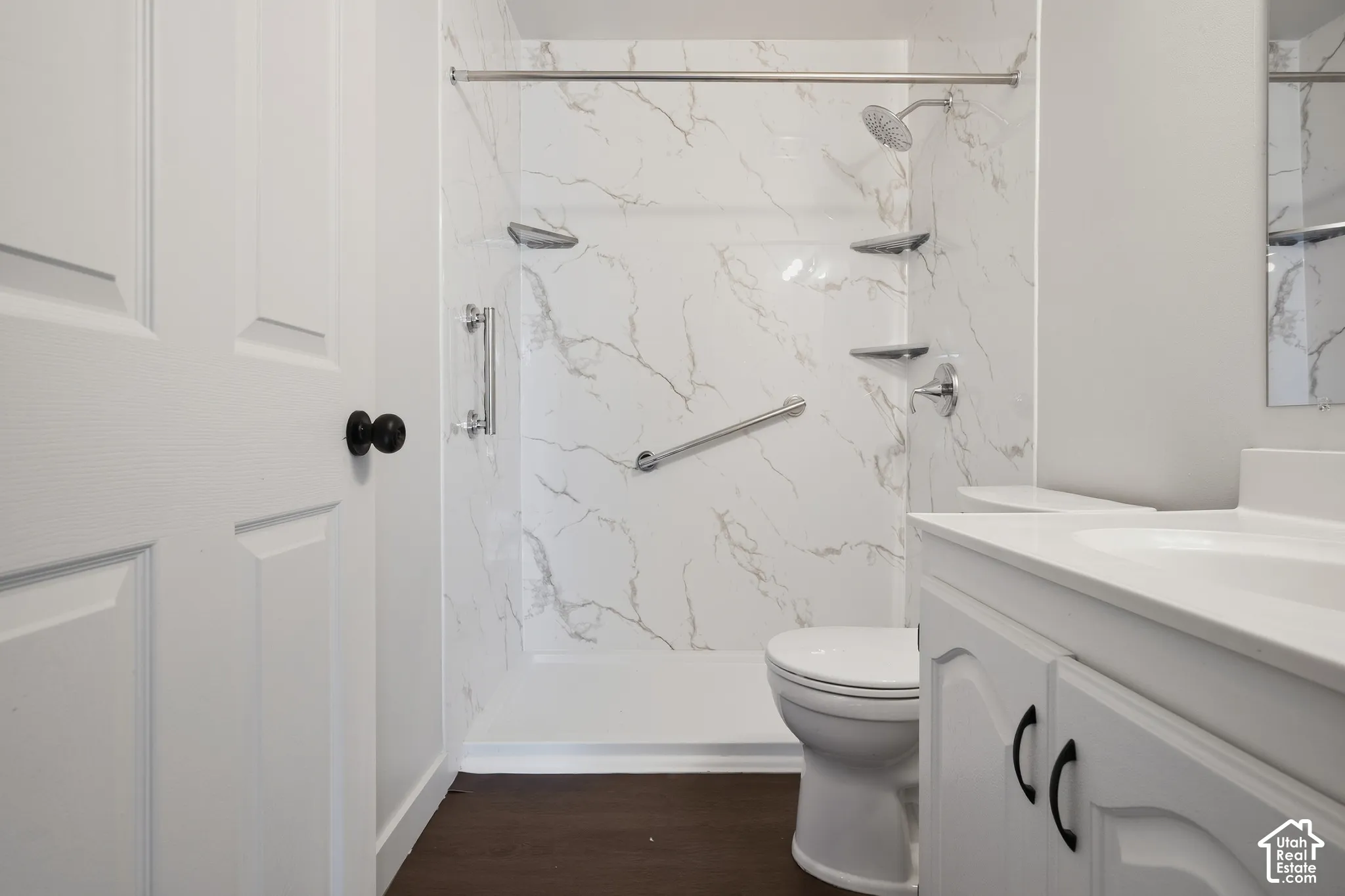 Walk-in shower with marble-look surround, integrated shelving, and chrome fixtures