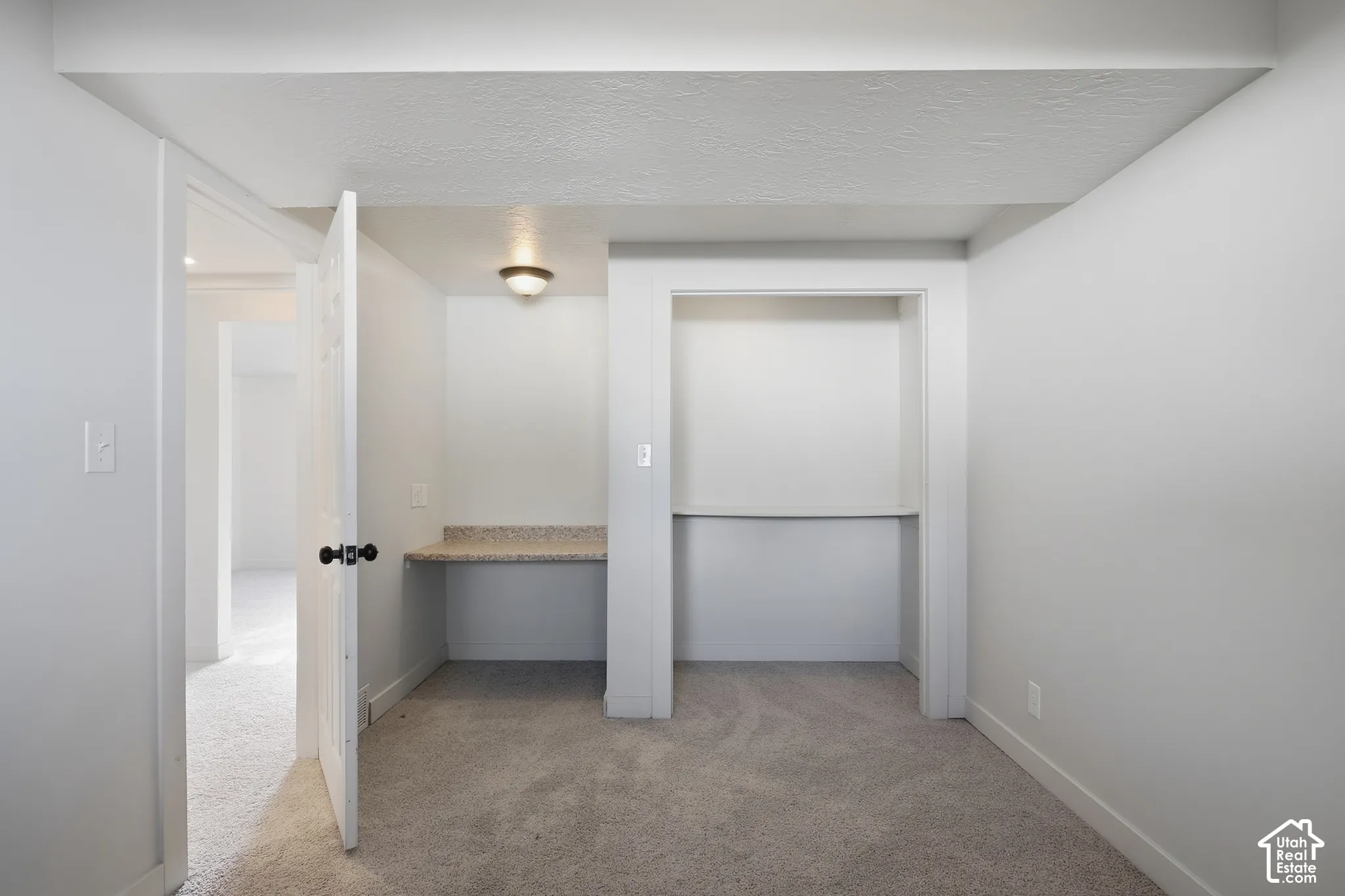Built-in desk with a speckled countertop, integrated shelving, and flush-mount ceiling lighting