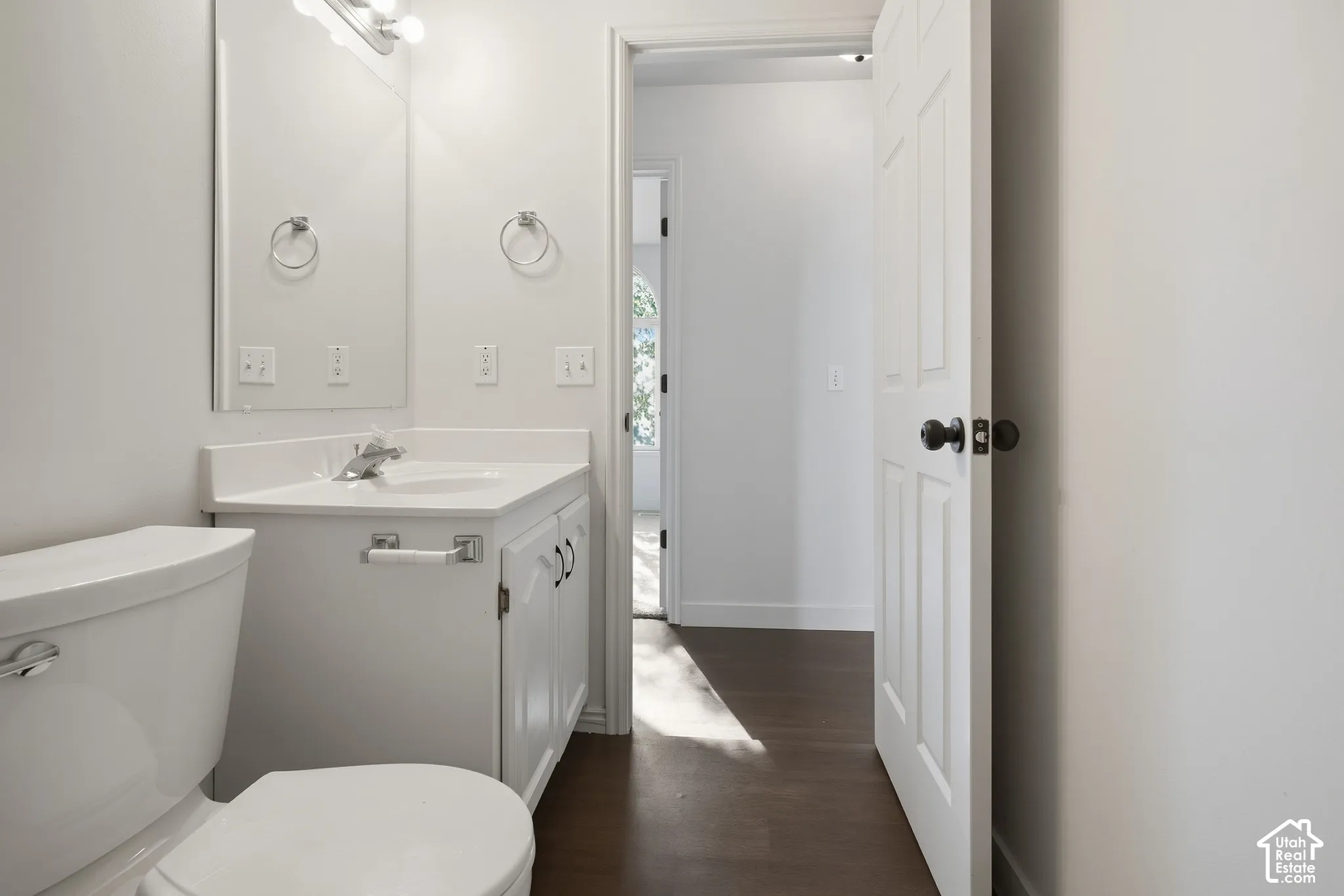 White vanity with an integrated sink and countertop, polished chrome faucet, and overhead vanity lighting