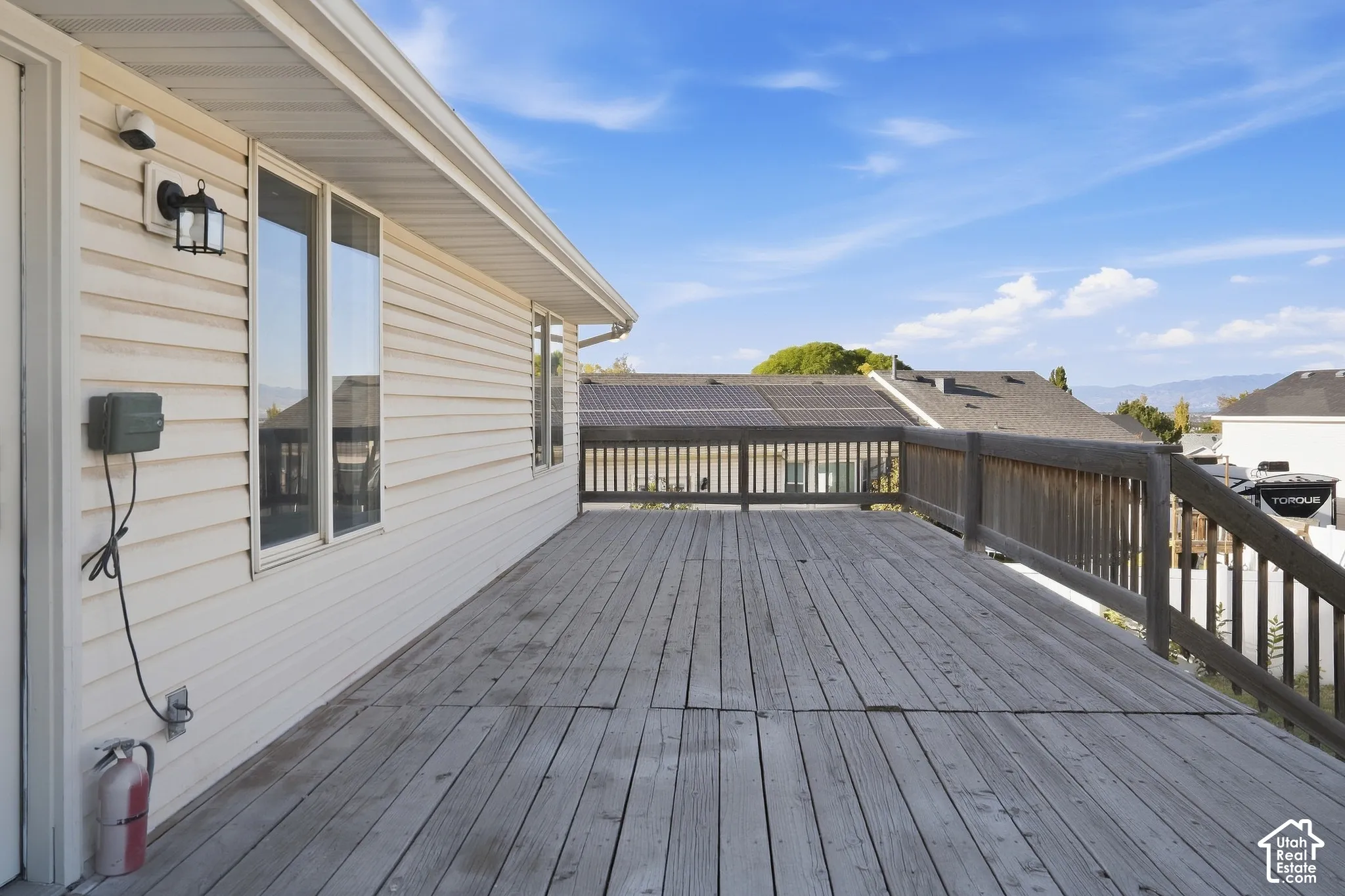 Wood deck with wood railing, white siding exterior, and exterior lighting fixture
