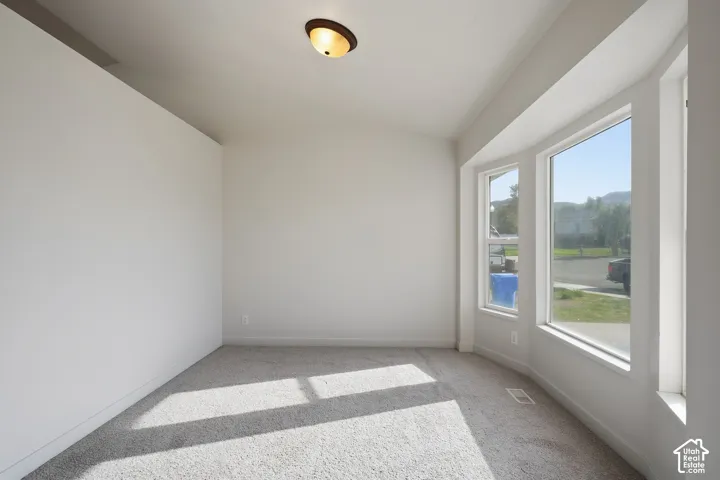 Bay window with white trim, vaulted ceiling, and flush mount light fixture