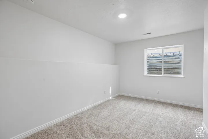 Recessed ceiling lighting, light neutral paint, window with window well, light-toned carpeting