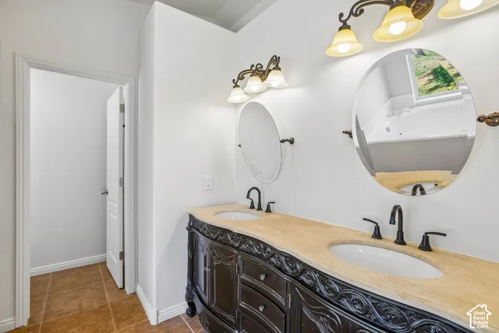 Double vanity with decorative dark wood cabinetry, dual oval mirrors, and elegant wall-mounted lighting