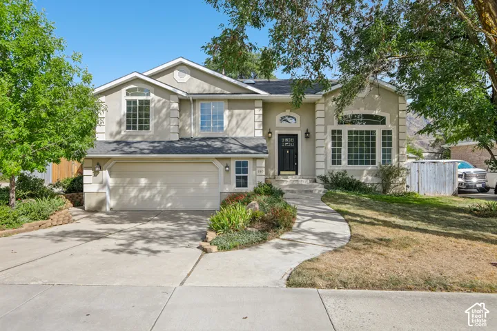 Stucco exterior with decorative trim, arched and rectangular windows, a two-car garage, and a curved concrete walkway